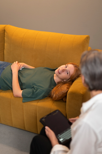 Client resting on mustard sofa during session